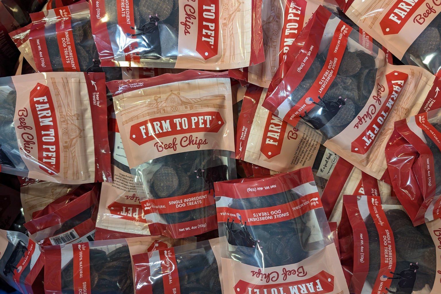 A pile of Farmto-pettreats Beef Chip bags on a table.
