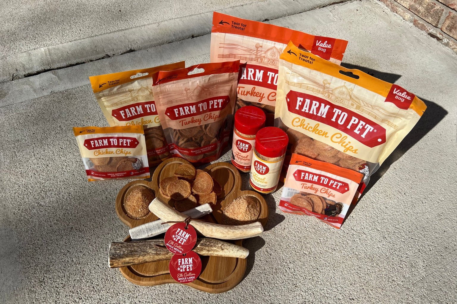 Farmto-pettreats Dog Treat, Chews, and Toppers Collection displayed on a  paw board.