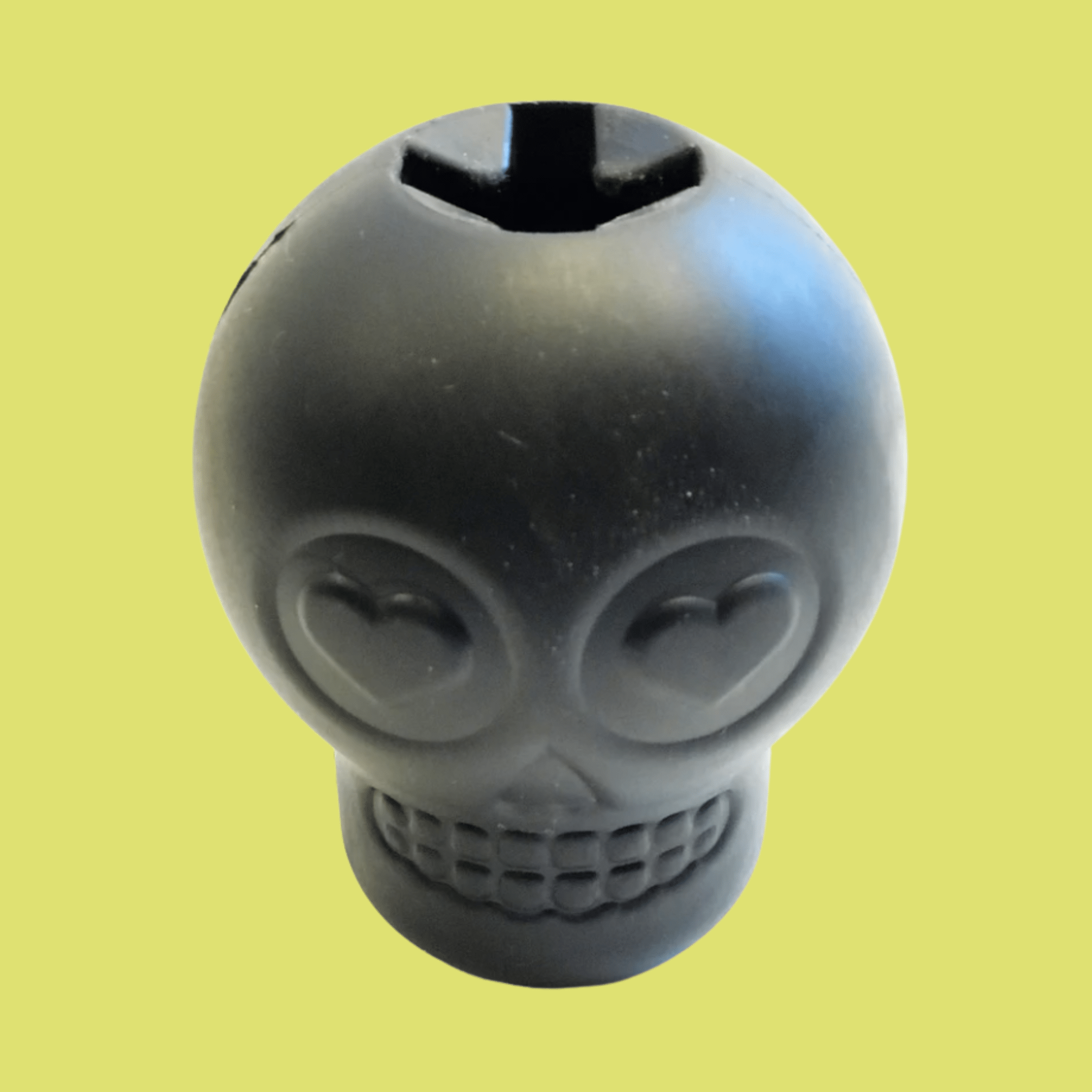 Farmto-pettreats Dog Treat Dispenser Black skull-shaped showing top view  on a yellow background