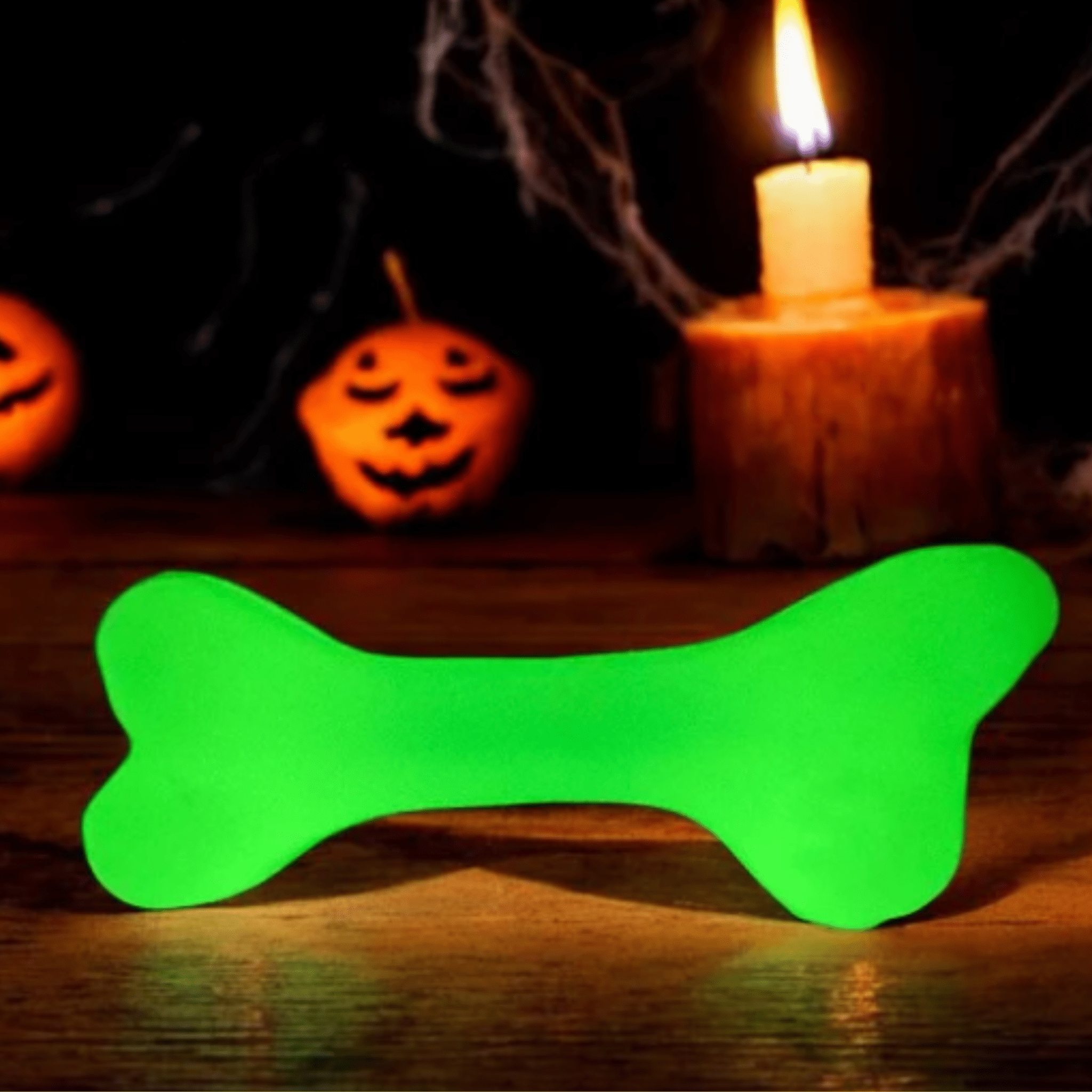 Farmto-pettreats Dog Treat Dispenser white bone that glows in dark Green  on a wooden surface with Halloween decorations in the background.