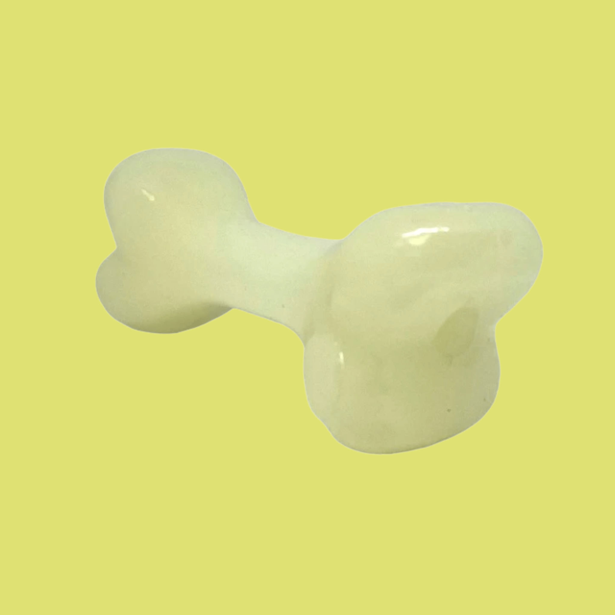 Farmto-pettreats Dog Treat Dispenser White bone that glows in the dark sideview on a yellow background.