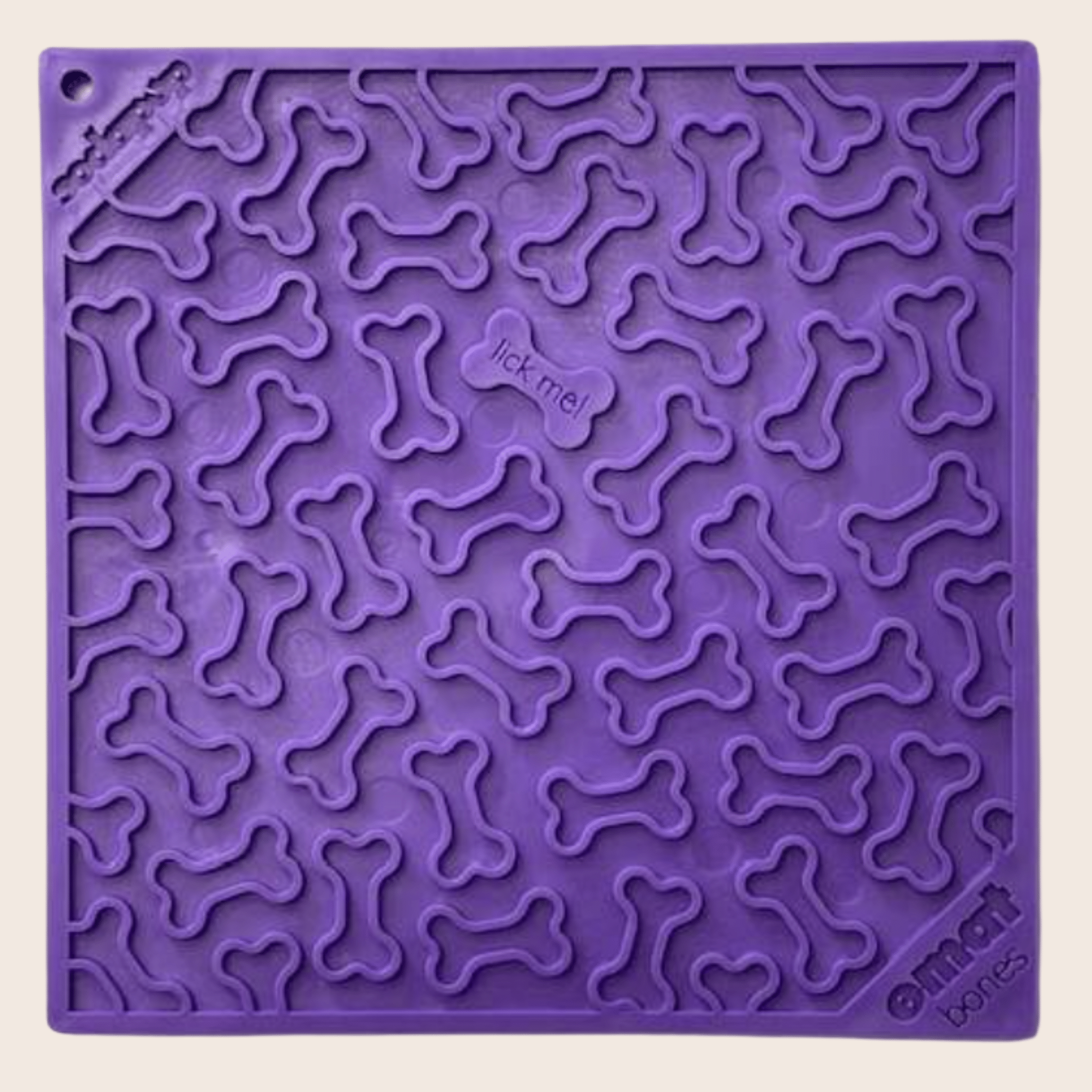 A Farmto-pettreats Purple dog bone lick mat with bone patterns and 'lick me!' text on a beige background.
