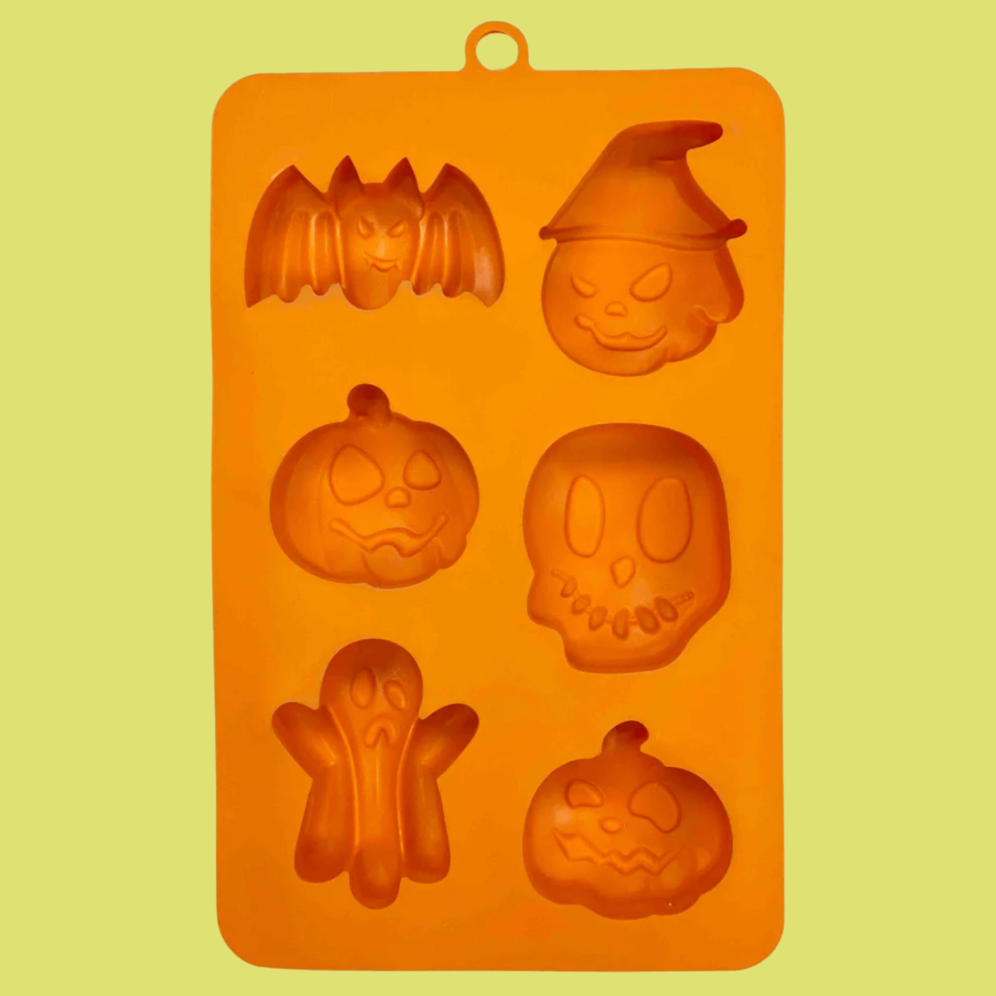 Farmto-pettreats  Halloween Pet Treat Mold in Orange silicone with Halloween-themed shapes on a yellow background front of mold. 