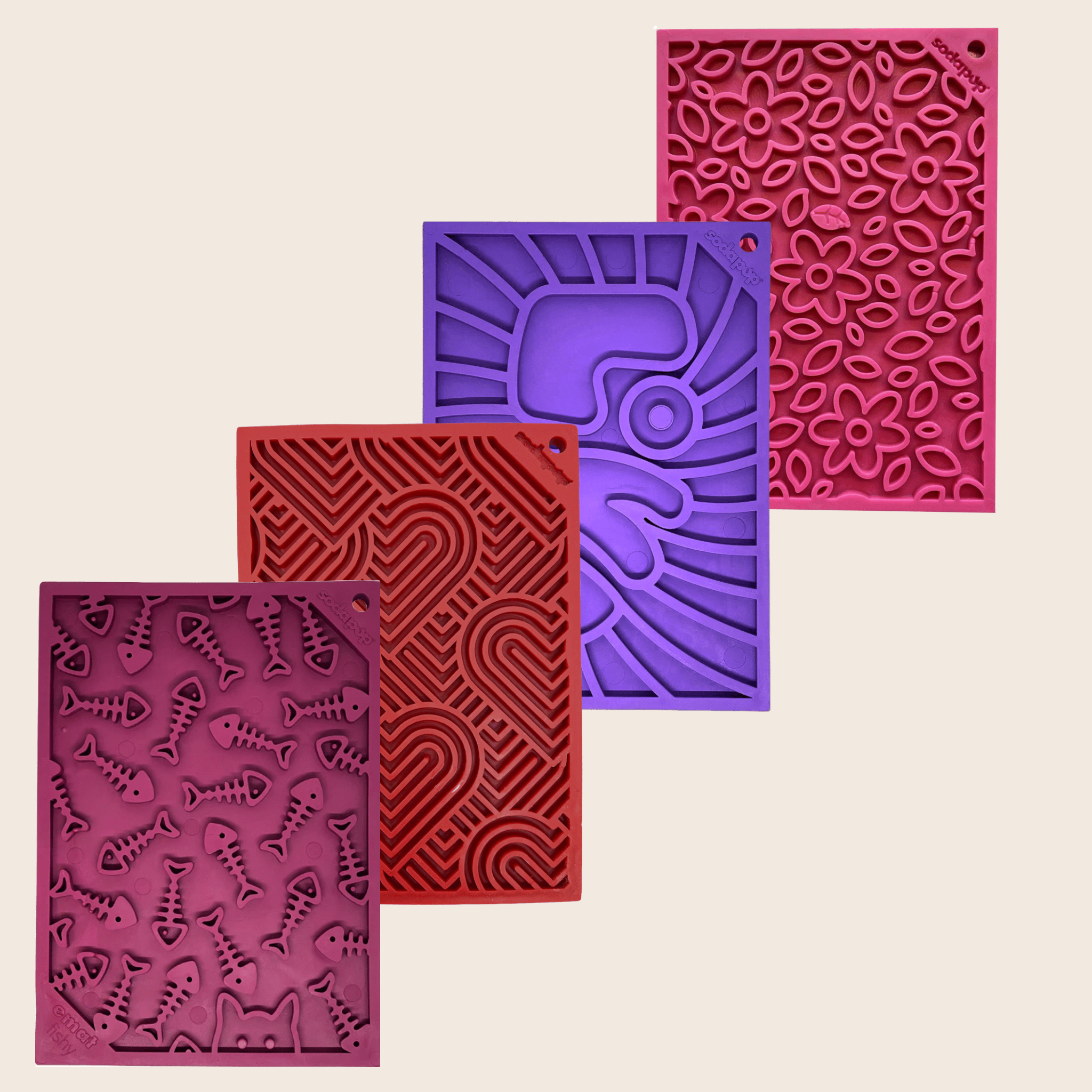 Four textured silicone lick mats from Farmto-pettreats in maroon, purple, red, and pink on a beige background.